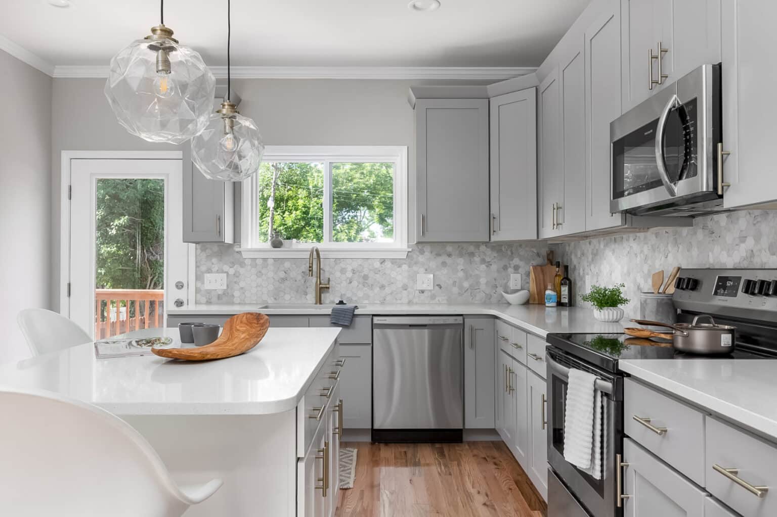 A kitchen with stainless steel appliances, tiled backsplash, and large island.