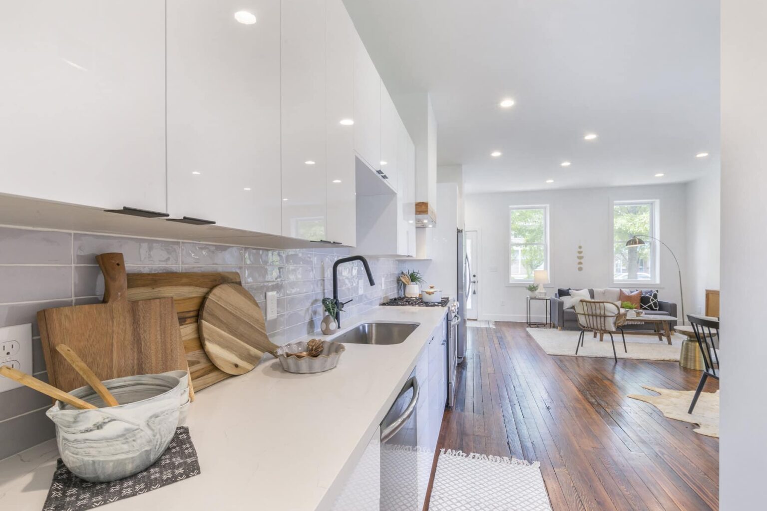 A modern kitchen with hardwood floors opens up into a spacious abd bright living area.