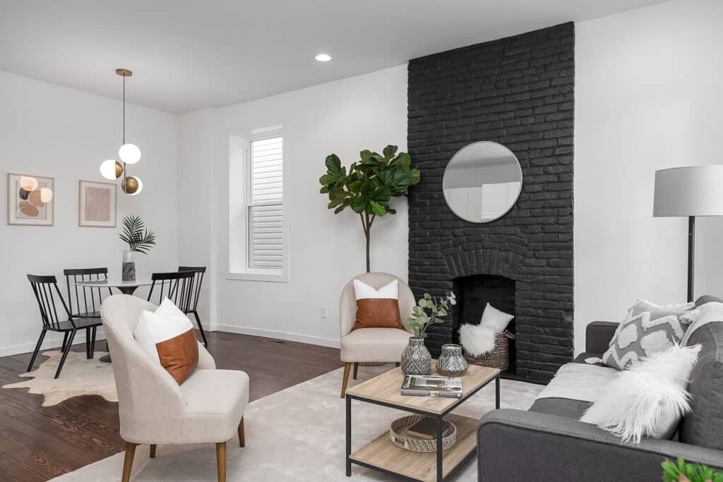 A living room with a black brick fireplace opens into a small dining area.
